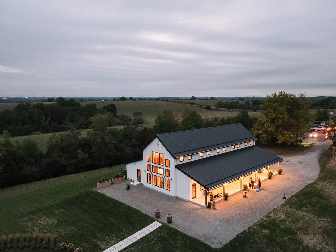 Farmhill Weddings venue - aerial view of the beautiful timber-frame barn with warm lighting surrounded by rolling countryside